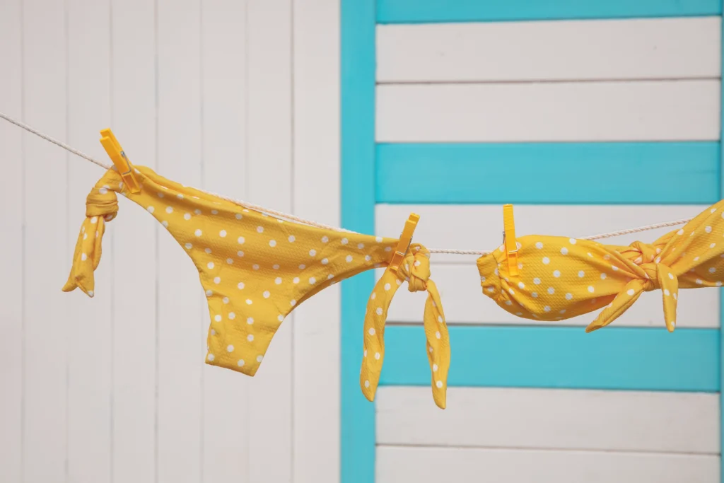 Biquíni amarelo a secar ao ar livre após a lavagem, ilustrando como lavar biquínis sem danificar o tecido nem comprometer a elasticidade.